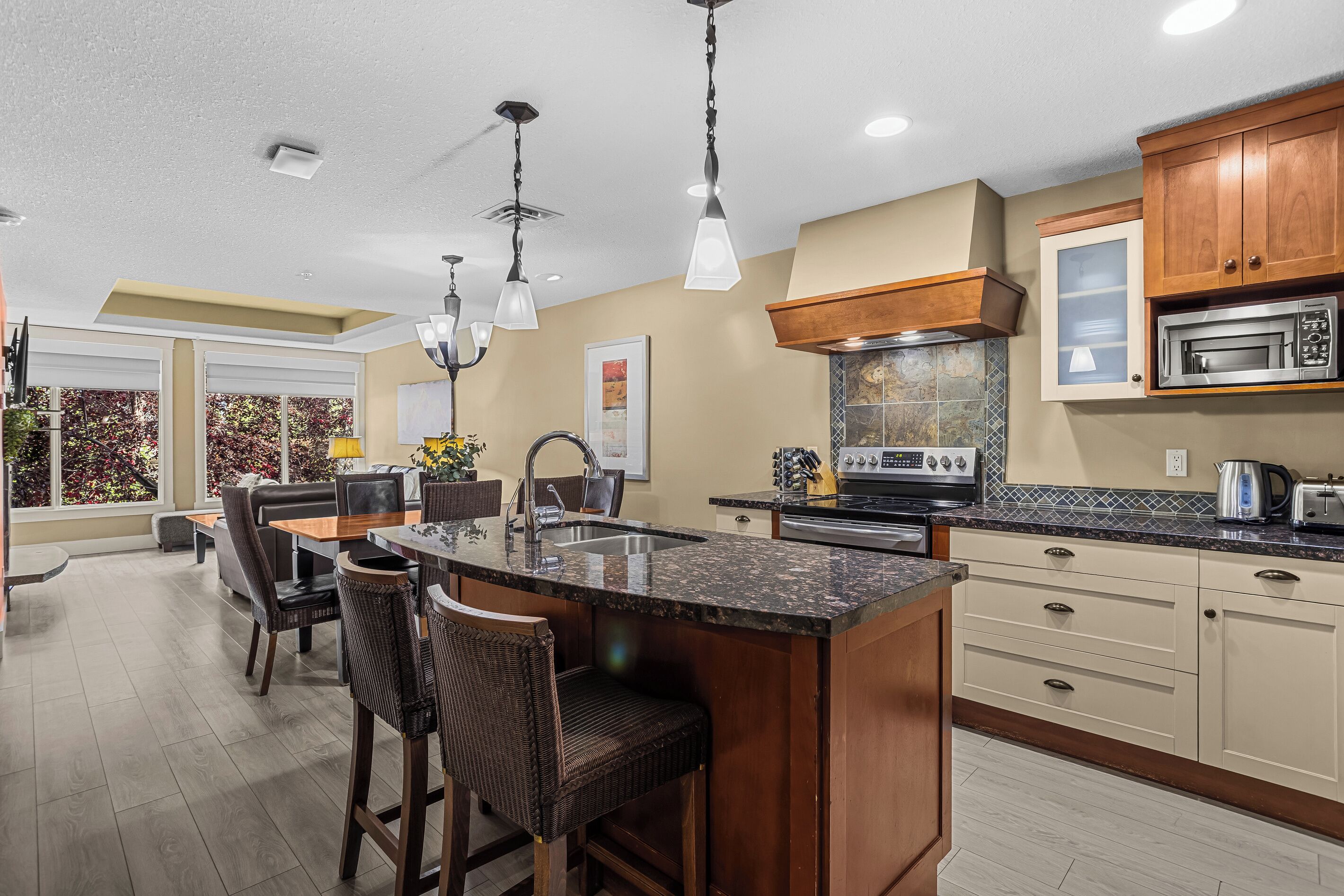 A modern kitchen with a central island, stainless steel appliances, and a dining area with a view.