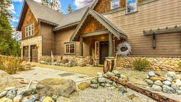 Cozy cabin with a stone hearth and large window above the door, set amidst a natural landscape.