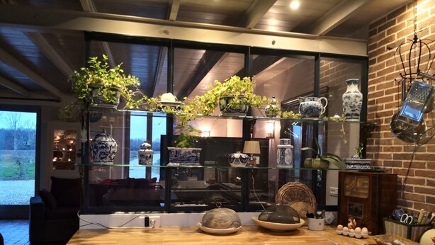 A kitchen with a wooden countertop, a glass display case with kitchenware, and a brick wall. - la Fermette des Petites-haies , un Hymne a la Douceur de Vivre (Lorris)