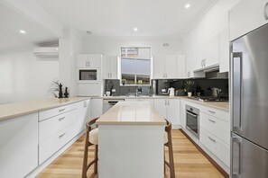 A modern kitchen with white cabinetry, a central island, stainless steel appliances, and a window above the sink.