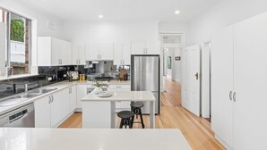 Una cocina moderna con armarios blancos, electrodomésticos de acero inoxidable y una isla central con taburetes.