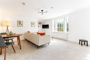 Un salon moderne avec un canapé, une table à manger et un téléviseur.