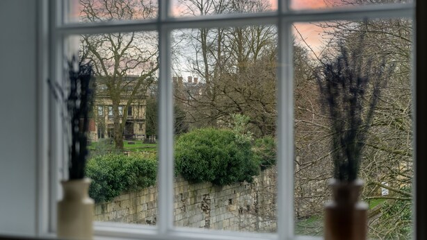 A view through a window with bare trees and a stone wall, with a building in the background. - Apartment 8 - Bootham House - sleeps 2 guests  in 1 bedroom (York)