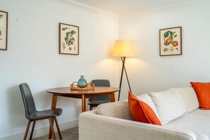 A room with a dining table, chairs, a lamp, a sofa, and framed botanical prints on the walls. - Apartment 8 - Bootham House - sleeps 2 guests  in 1 bedroom (York)