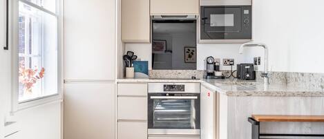 A modern kitchen with white cabinetry, a built-in oven, a microwave, and a sink.