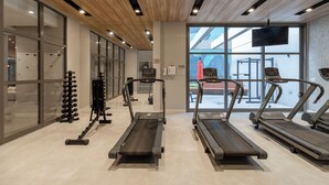 Et moderne fitnesscenter med løbebånd, træningsmaskiner og et stort vindue med udsigt over det fri.