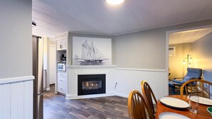 A dining area with a fireplace, wooden flooring, and a dining table with chairs. - Cameron's Peaceful Pines, King Bed! (Bayfield)