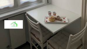 A small table with two chairs, a poster on the wall, and a window with curtains. - Lavi House with Box (Rapallo)