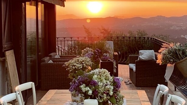Ein Esstisch für zwei Personen mit Blick auf den Sonnenuntergang über den Bergen.