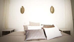 Ein Schlafzimmer mit einem großen Bett, mehreren Kissen, zwei Nachttischen und dekorativen Wandleuchten.