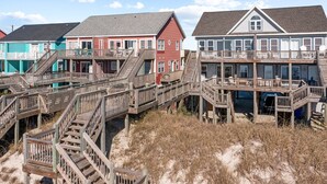 Une propriété située en bord de mer, dotée de plusieurs terrasses en bois et d’escaliers menant à la plage.