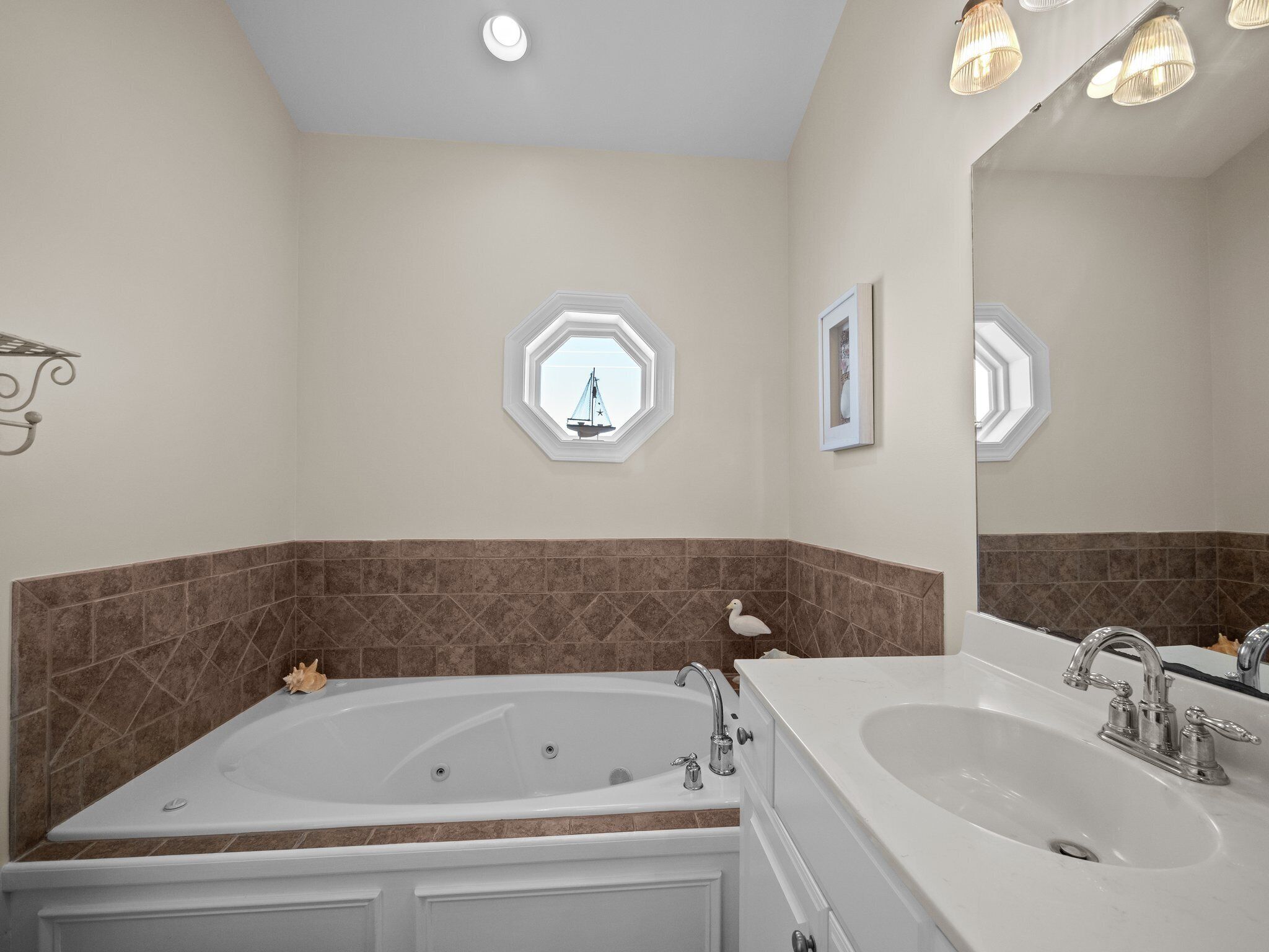 A bathroom with a large bathtub, two sinks, and decorative wall tiles.