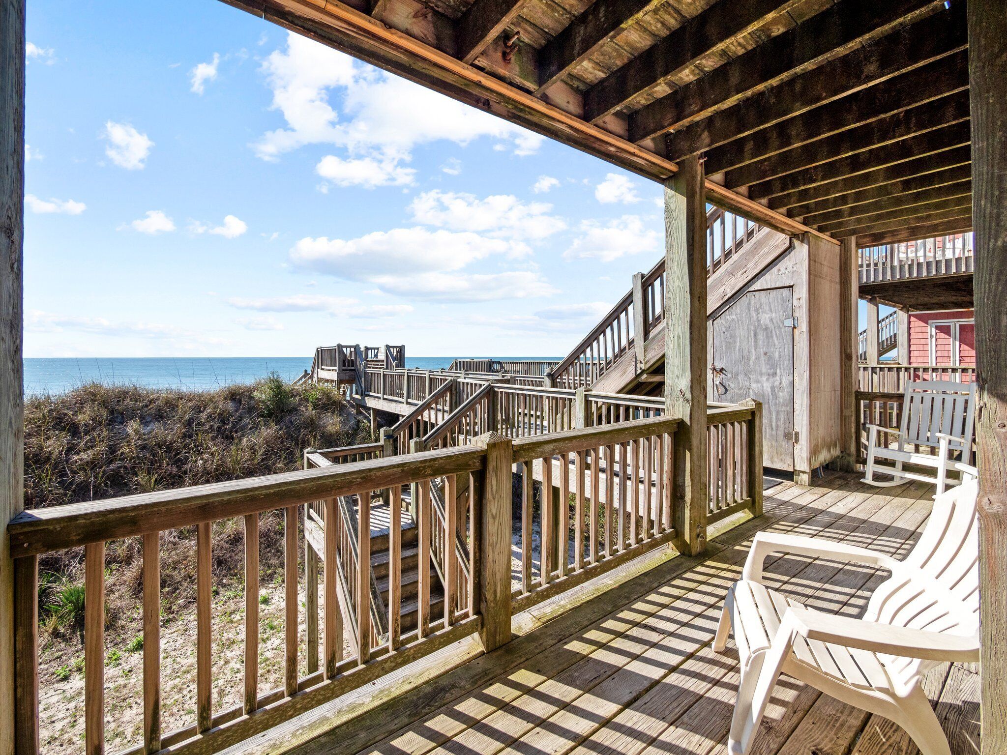 A wooden deck with a view of the beach and ocean.