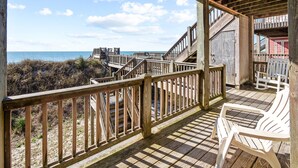 Une terrasse en bois offrant une vue sur la plage et l’océan.