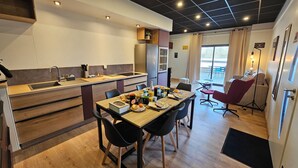Une cuisine moderne dotée d’un îlot central, d’une table à manger avec des chaises et donnant sur un espace extérieur.
