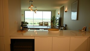 Una cocina moderna con un ventanal grande, un comedor con vistas e iluminación colgante.
