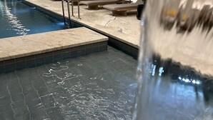 Una piscina con tumbonas y un elemento acuático.