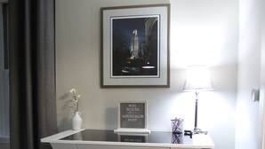Een modern bureau met een lijst met afbeelding, een bordje dat WiFi aangeeft, een vaas met bloemen en een bureaulamp.