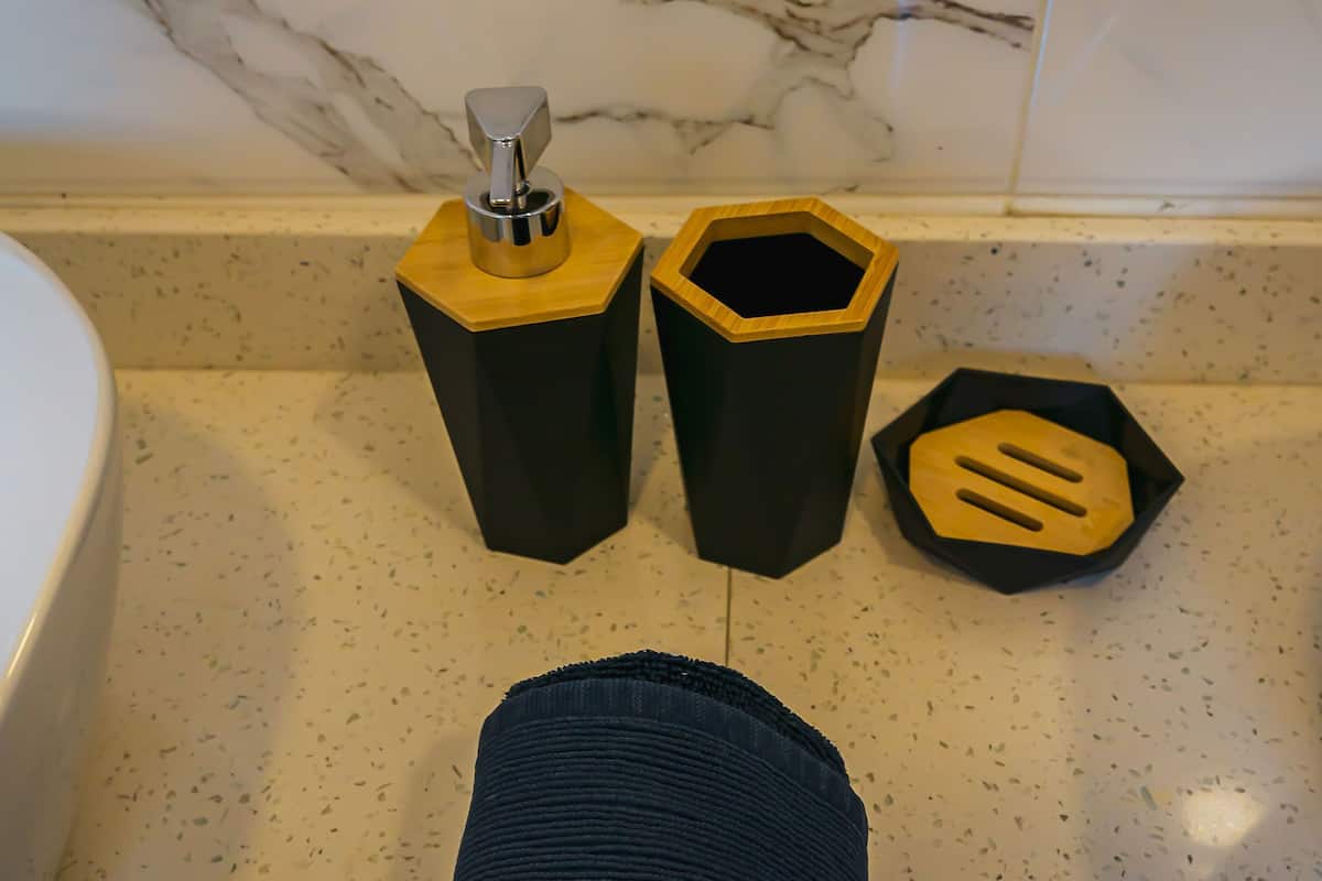 Une salle de bain avec un mur en marbre, une baignoire blanche et une serviette bleu foncé posée sur le sol.