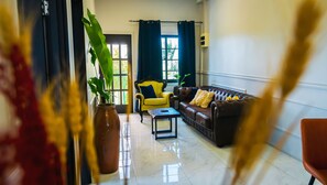 A living room with a yellow armchair, a brown sofa, a coffee table, and a potted plant. - Colonial Wolf Oasis (Paramaribo)