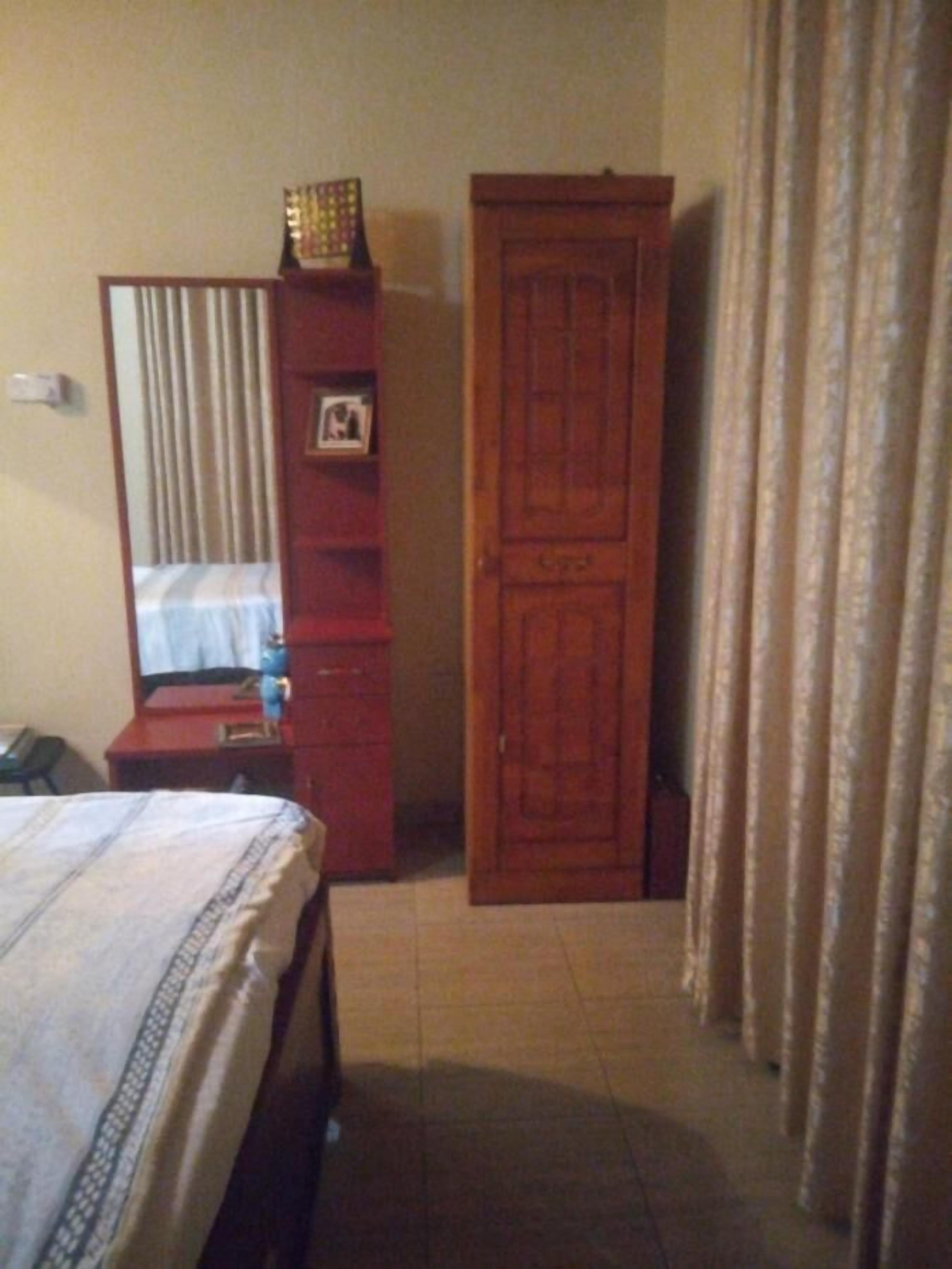 Un dormitorio con cama, armario, espejo y cortina.