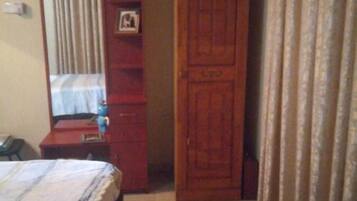 Un dormitorio con cama, armario, espejo y cortina.
