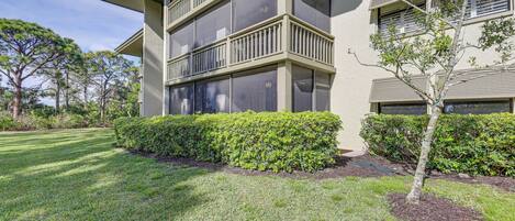 A multi-story building with balconies, a well-maintained lawn, and mature trees.
