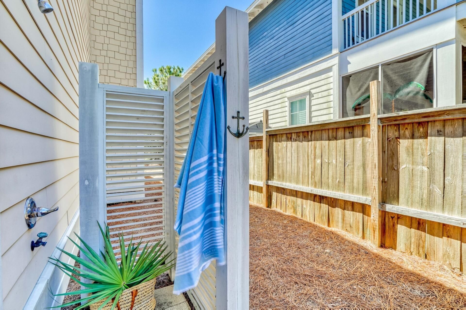 A wooden gate with a blue towel hanging on it, a wooden fence, and a small potted plant.