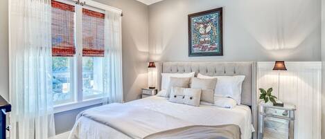 A bedroom with a large bed, two bedside tables, a ceiling fan, and a window with blinds.