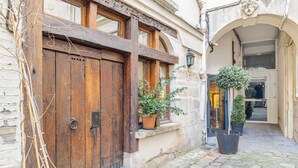 A cobblestone courtyard with a wooden door, potted plants, and a stone wall. - Aquipic, 2BR/1BA, 4 people (París)
