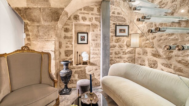 A stone-walled room with a vintage sofa, a classic armchair, and a decorative vase. - Aquipic, 2BR/1BA, 4 people (París)
