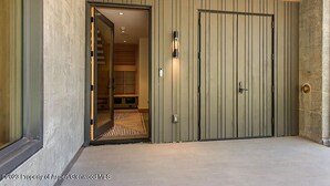 A modern entrance with a wooden ceiling, a sliding door, and a visible staircase leading to an interior space.