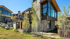 A modern two-story house with large windows and a wooden roof.