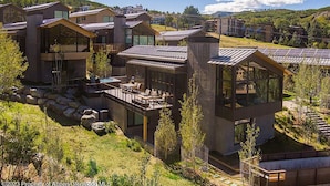 A modern residential complex with multiple houses featuring large windows, outdoor decks, and solar panels.