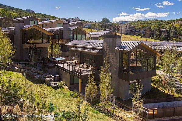 A modern residential complex with multiple houses featuring large windows, outdoor decks, and solar panels.