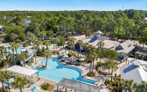 A resort with a large swimming pool, palm trees, and a variety of buildings.