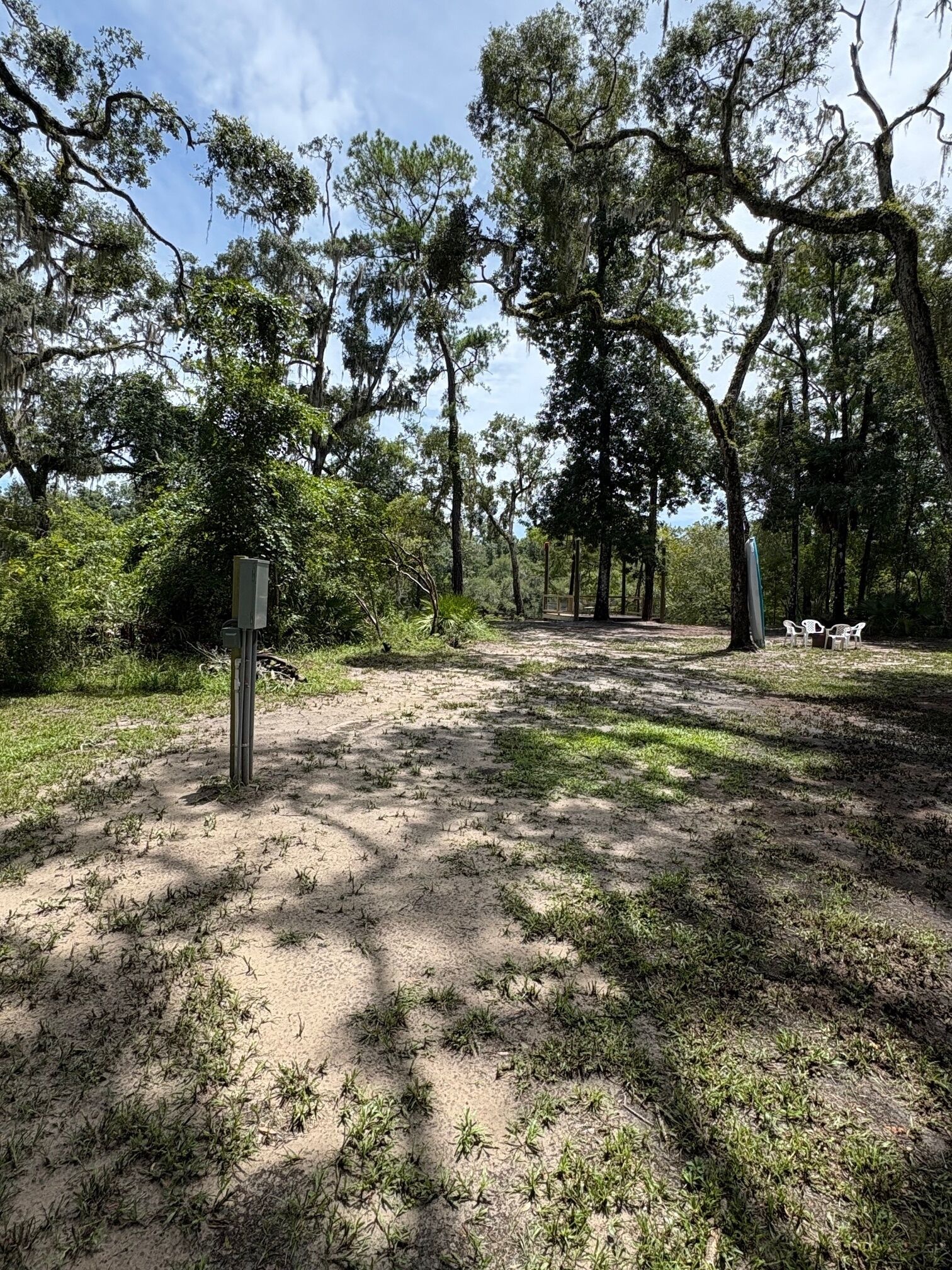 Um camping com árvores, um caminho de terra e um sinalizador.