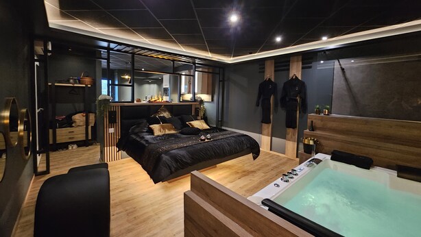 Un dormitorio moderno con una cama grande, un escritorio de madera, un espejo y una bañera.