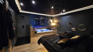 Un dormitorio moderno con una cama grande, una bañera integrada y un tocador con espejo.