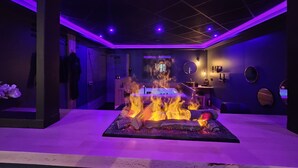 Un interior moderno con una chimenea central, una zona de bar y un espacio para sentarse.