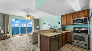 A kitchen with wooden cabinets, stainless steel appliances, and a view to the outside.