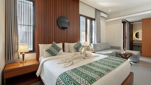 Hotellihuone, jossa on suuri sänky, sohva, pyöreä pöytä ja peili.