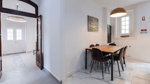 Un coin repas avec une table et des chaises en bois, un tableau au mur et une suspension lumineuse.