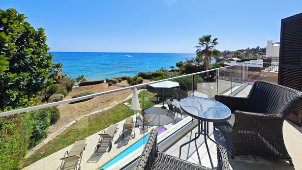 Ein Balkon mit Meerblick, Gartenmöbel und einem Swimmingpool.