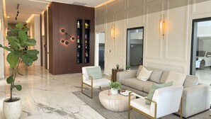 Ein modernes Wohnzimmer mit Marmorboden, einer Sofagarnitur, einem Couchtisch und einer großen Pflanze.
