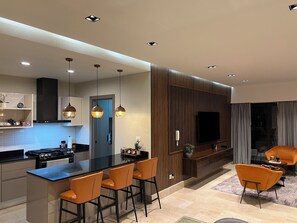 A modern kitchen with a central island, bar stools, and pendant lighting.