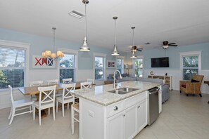 A spacious kitchen with white cabinetry, a granite countertop, and pendant lighting.