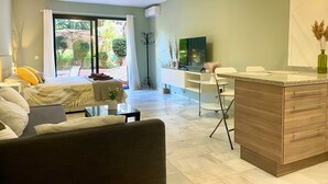 A modern living room with a sofa, a coffee table, a TV, and a dining area with a counter and chairs. - Banus Elegant Modern Estudio Next to the Beach (Marbella)