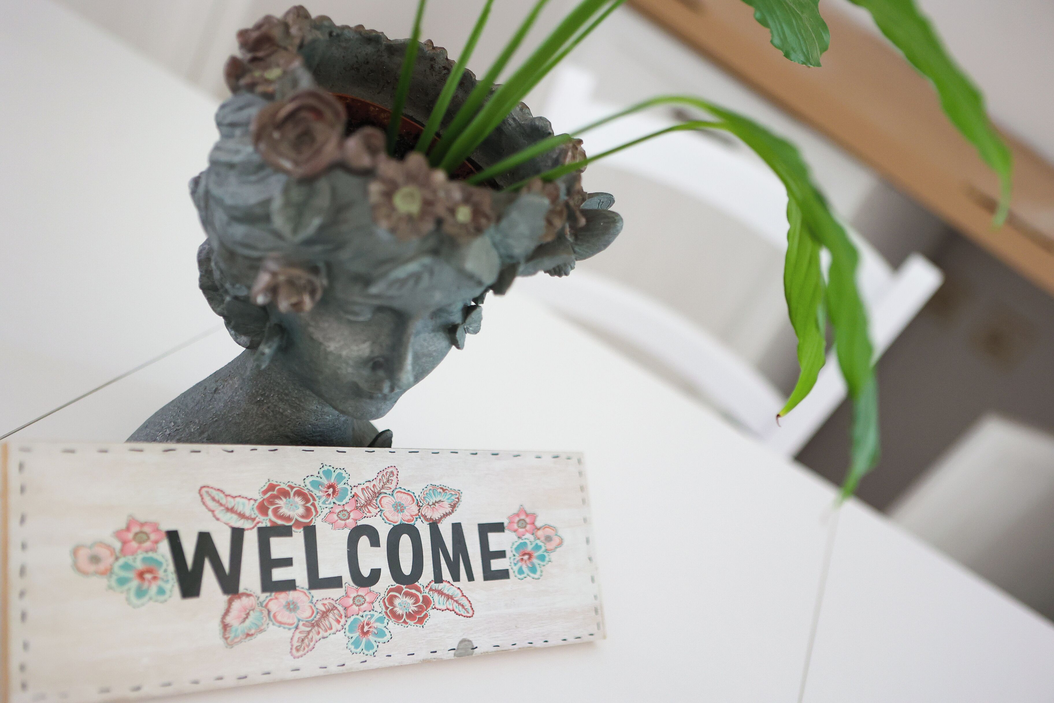 Une enseigne accueillante agrémentée de décorations florales et d’une sculpture représentant la tête d’une femme.