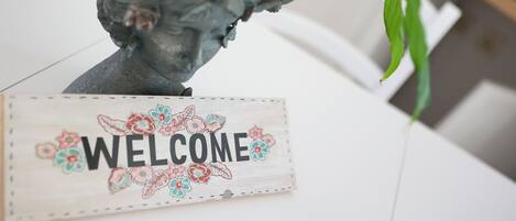 A welcome sign with floral decorations and a sculpture of a woman's head.